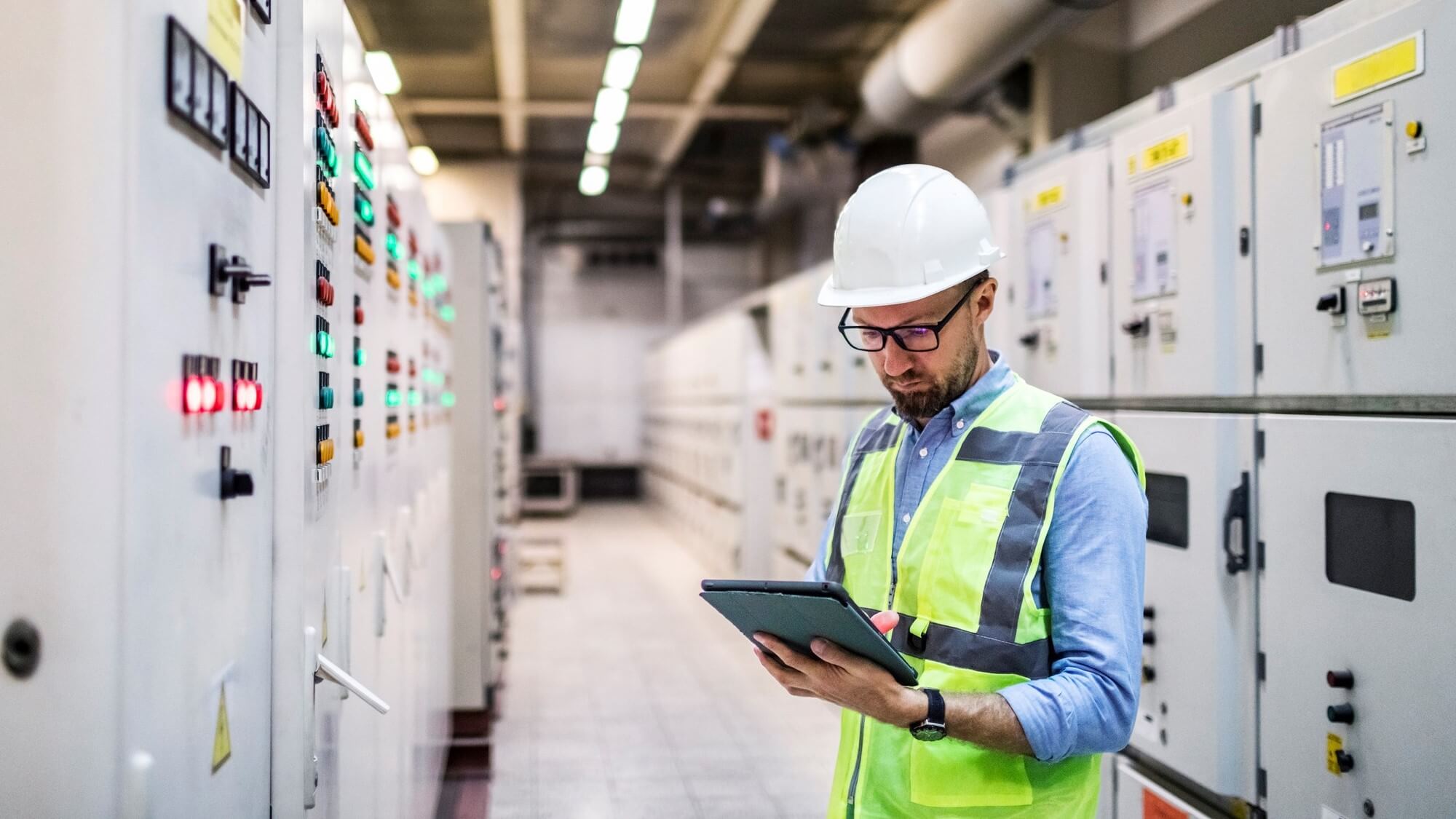 Electrical engineer checking power at control room using digital tablet